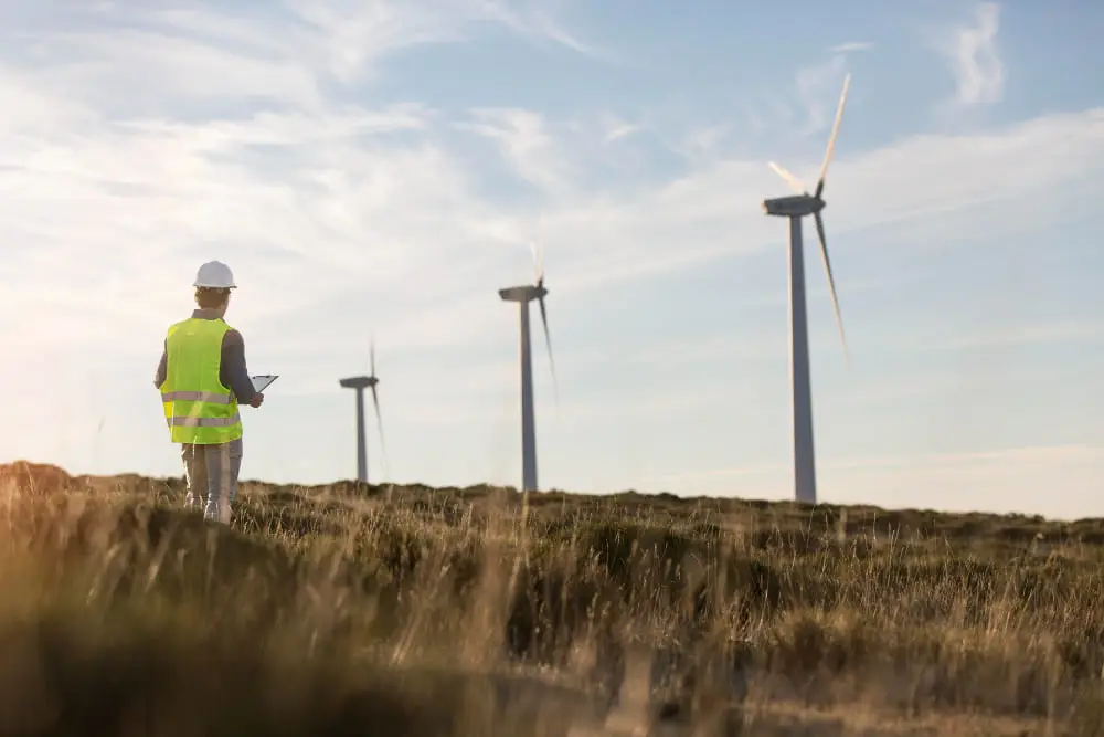 A man in a hard hat stood in front of the wind turbines.