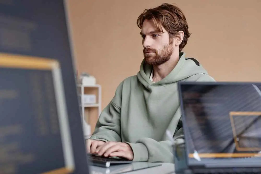 IT developer in hoody looking at computer screen